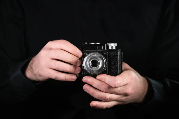 Man photographer holding a camera. Shooting process. Retro 35mm film photo camera on black background. — Stock Photo, Image