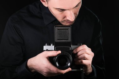 Elinde kamera olan bir fotoğrafçı. Çekim işlemi. Siyah arka planda retro fotoğraf makinesi orta format.