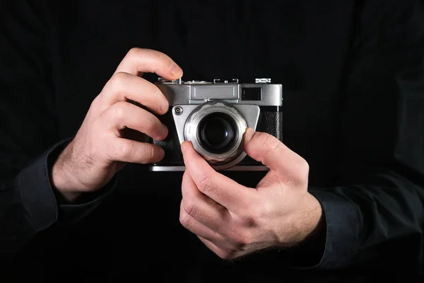 Man photographer holding a camera. Shooting process. Retro 35mm film photo camera on black background. — Stock Photo, Image