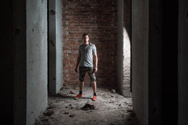 Bir onay gömlek ve şort bir tuğla duvara giyen genç adam.