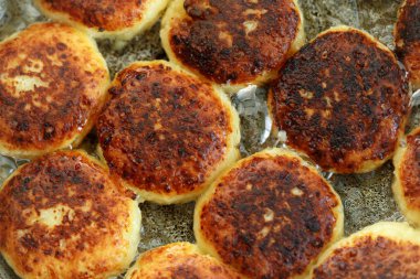 Tavada lezzetli kızarmış syrniki closeup pişirme işlemi. Ukrayna, Beyaz Rusya ve Rusya'da geleneksel. Sağlıklı bir ev yemeği kavramı.