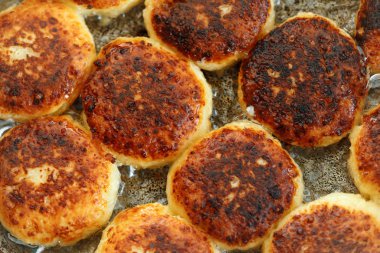 Tavada lezzetli kızarmış syrniki closeup pişirme işlemi. Ukrayna, Beyaz Rusya ve Rusya'da geleneksel. Sağlıklı bir ev yemeği kavramı.