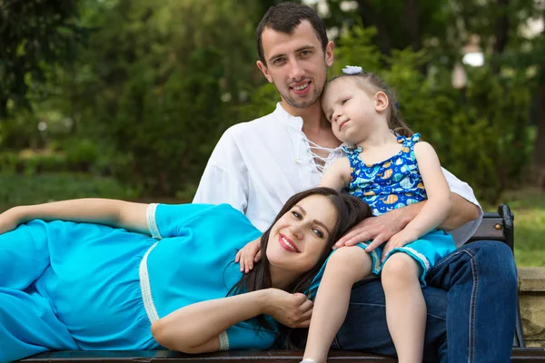Parkta bir bankta oturan aile. Hamile bir kadın. Mutlu aile hayatı kavramı. — Stok fotoğraf