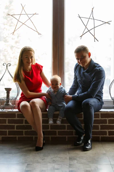 Parents and their child sitting at the window. Mom, dad and baby. Portrait of young family. Happy family life. Man was born. — Stockfoto