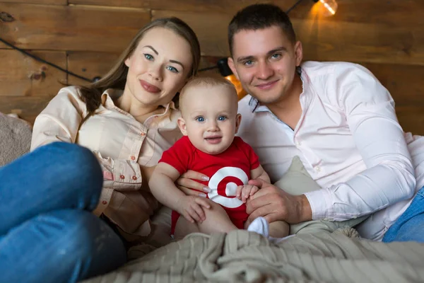 Föräldrar och deras barn ligger på sängen. Mamma, pappa och barn. Porträtt av en ung familj. Ett lyckligt familjeliv. Människan föddes. — Stockfoto