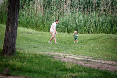 Baba ve oğul gölde oynuyorlar. Parkta yürü. Aile hayatı. Yatay çerçeveli çekim.