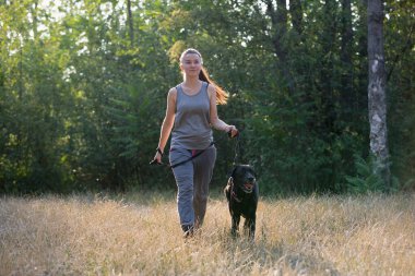 Siyah Labrador 'la parkta yürüyen çekici genç bir kız. Sağlıklı bir yaşam tarzı. En sevdiğiniz evcil hayvanla yürüyün. Yatay çerçeveli çekim.