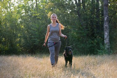 Güzel bir kız ve parkta siyah bir köpek. Spor yaşam tarzı. Yatay çerçeveli çekim.