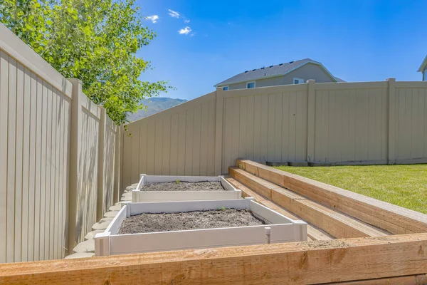 Empty growbeds in clean backyard with lawn