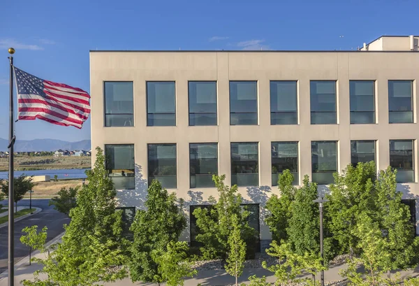 Bandera americana junto a edificio de oficinas y árboles — Foto de Stock