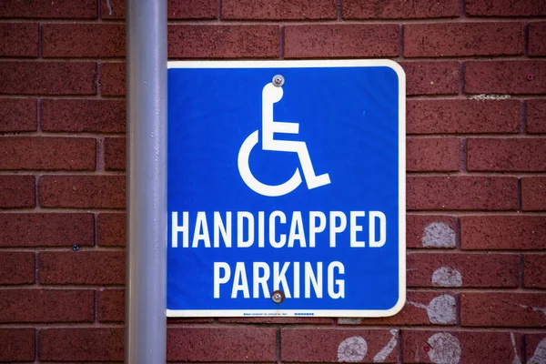 Handycapped Parking sign on brick wall with pipe — Stock Photo, Image