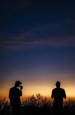 Güneş batıyor gibi iki adam kameralar ile stand