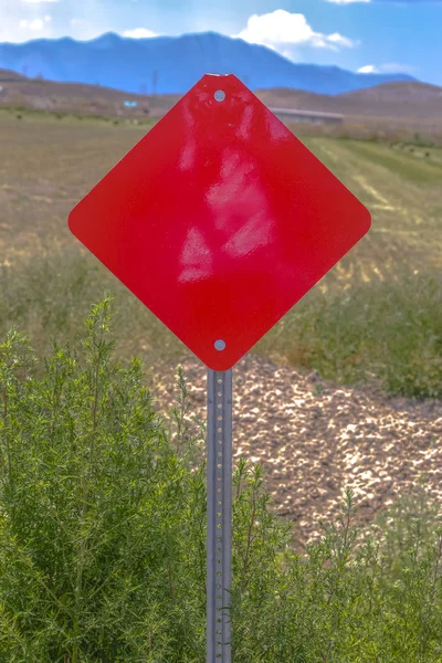 Red hazard sign showing end of paved road — Stock Photo, Image