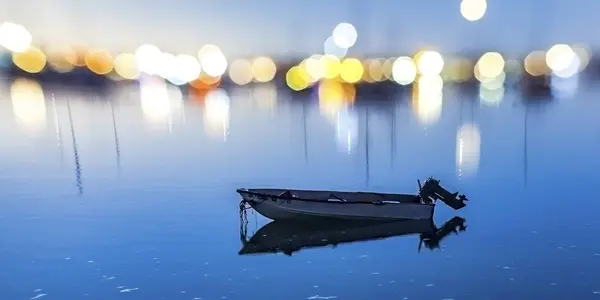 Bateau sur l'eau calme avec des lumières bokeh fond — Photo