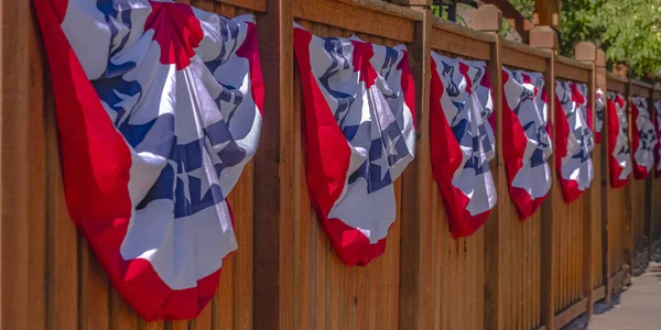 Patriotic flags hung on a wooden fence by sidewalk — Stock Photo, Image