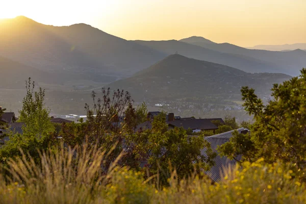 Pôr do sol nas montanhas atrás de casas e árvores — Fotografia de Stock