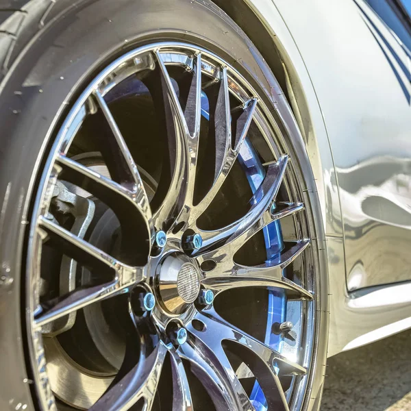 Llanta de neumático de plata con pernos azules de un coche blanco —  Fotos de Stock