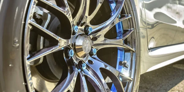 White car with silver tire rim and blue bolts — Stock Photo, Image