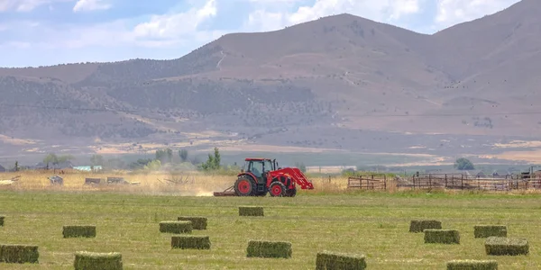 Tractor rojo en un campo con vista a la montaña — Foto de Stock