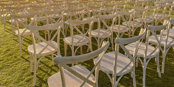 Подсвеченные солнцем белые стулья на ярко-зеленой лавке — стоковое фото