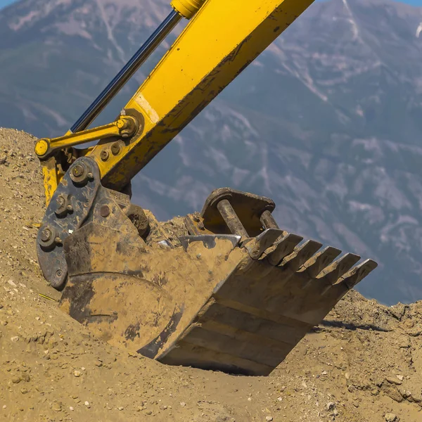 Arm of extractor scooping up dirt on a sunny day — Stock Photo, Image