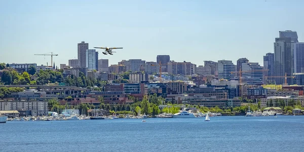 Float plane flying over lake and skyscrapers