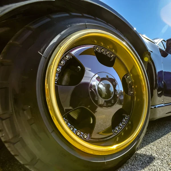 Gold rim and black spokes on a black cars wheels