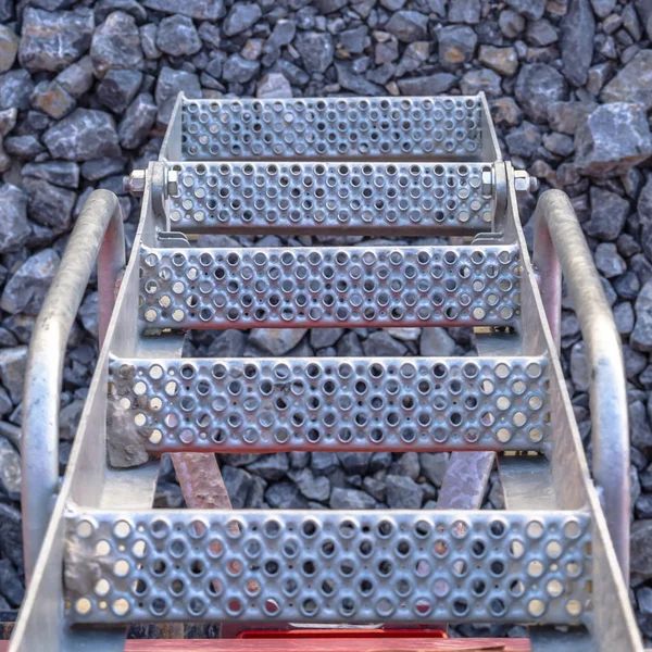 Perforated metal stairs on a stone ground