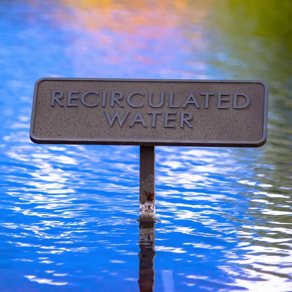 Recirculated water sign on reflective blue water