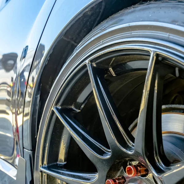 黒マグ ホイールと赤ラグナットのナットが付いている光沢のある車 — ストック写真