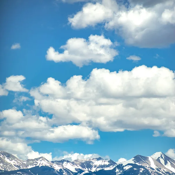 Montanha coberta de neve sob céu azul e nuvens — Fotografia de Stock