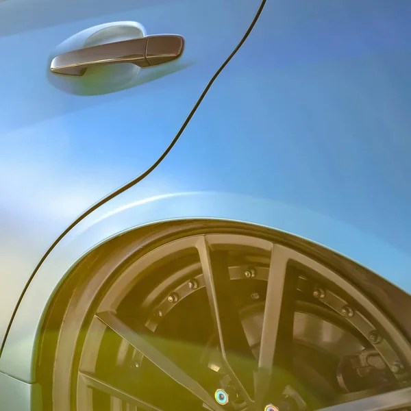 Sun reflecting on blue car with black tire rim — Stock Photo, Image