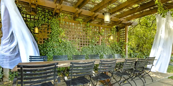 Table and chairs under a wooden pergola — Stock Photo, Image