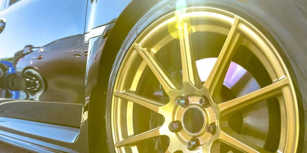 Llanta de neumático con radios dorados de un coche reflectante — Foto de Stock