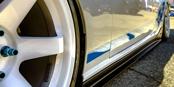 Carro branco com aro de roda branca e parafusos azuis — Fotografia de Stock