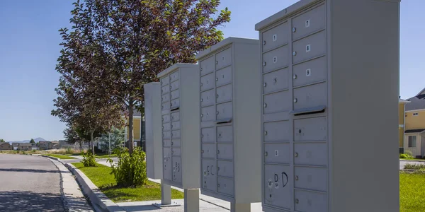 White mailboxes on a sunny landscaped sidewalk