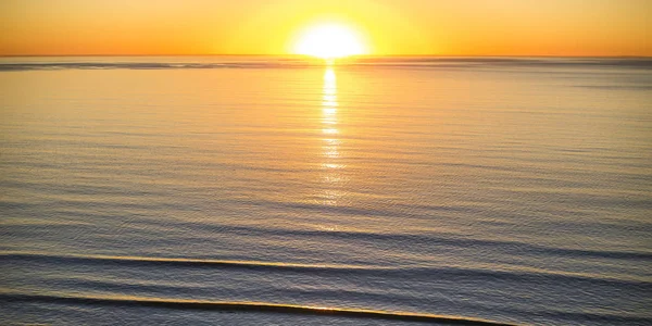 Bright sun and golden sky over the ocean at sunset