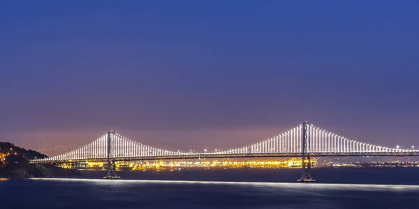 Glowing Bay Bridge sobre la bahía de San Francisco por la noche — Foto de Stock