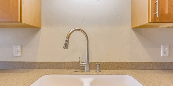 Faucet and sink against white wall with cabinets