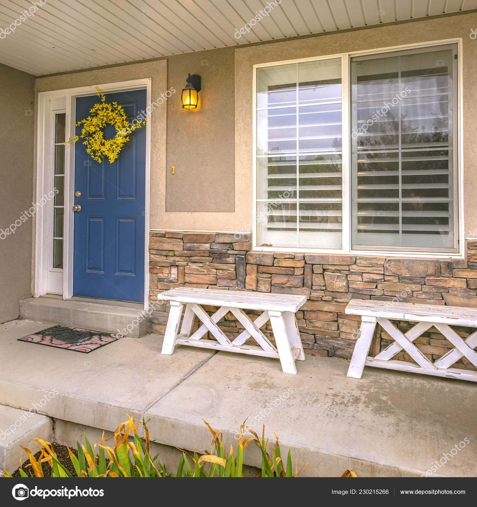 Blue Door With Wreath And Wooden Benches On Porch Stock Photo