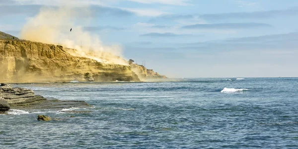 Person som hänger på en helikopter över cliff och ocean — Stockfoto