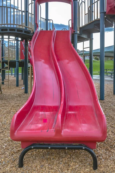 Red double slide and climbing bars on a playground