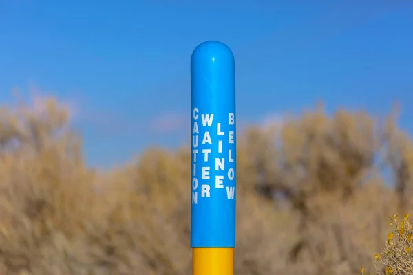 Vattenlinje nedanför skylt på en blå stolpe gul bas — Stockfoto