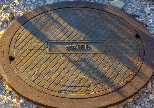 Tampa do buraco do homem com rótulo de água na frente — Fotografia de Stock