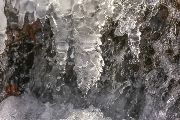 Eiszapfen bilden sich im fließenden Fluss kleiner Wasserfall — Stockfoto