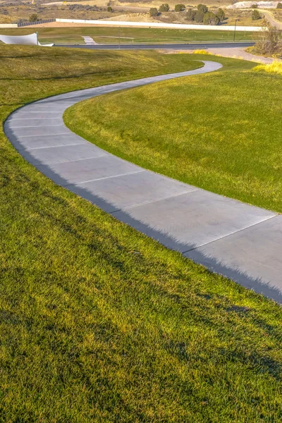 S curve sidewalk in park between lawn
