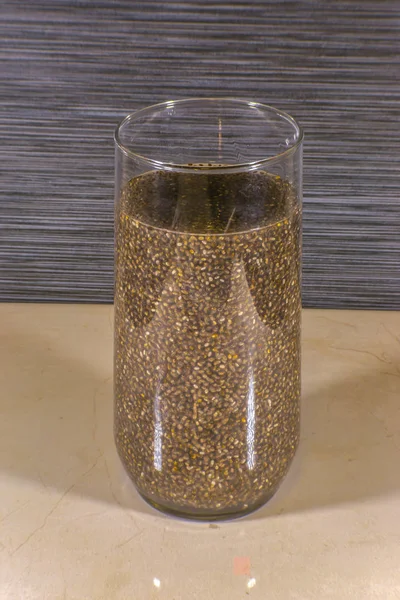 Vidro com sementes de chia em forma oval embebido em água — Fotografia de Stock