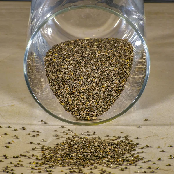 Spilled chia seeds from a reflective glass container