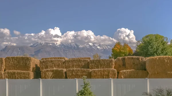 Some haystacks over white fence with mountains — Stock Photo, Image