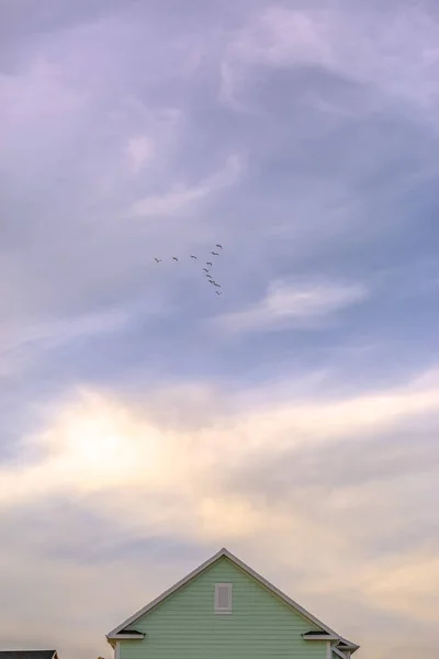 Πουλιά και συννεφιασμένο ουρανό πάνω από το σπίτι στη Χαραυγή Γιούτα — Φωτογραφία Αρχείου